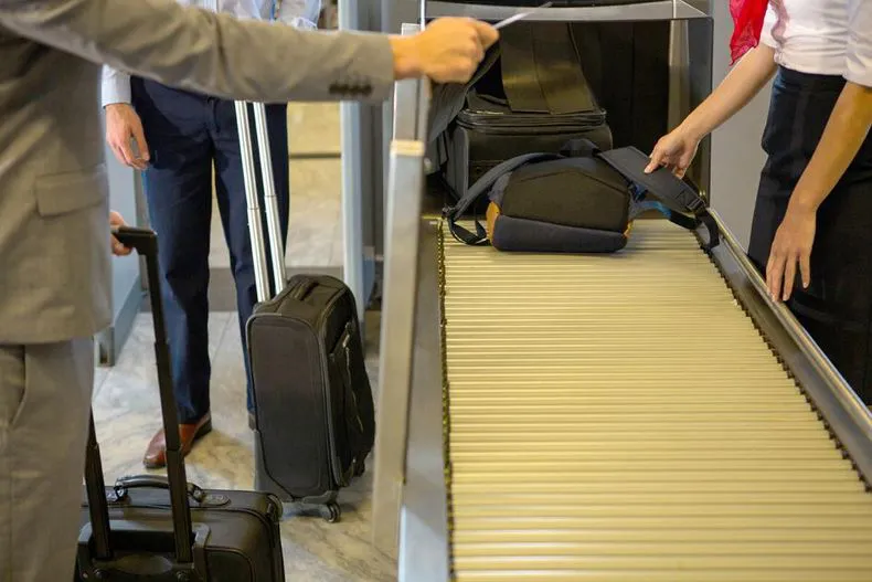 female-staff-checking-passengers-luggage-conveyor-beltjpg