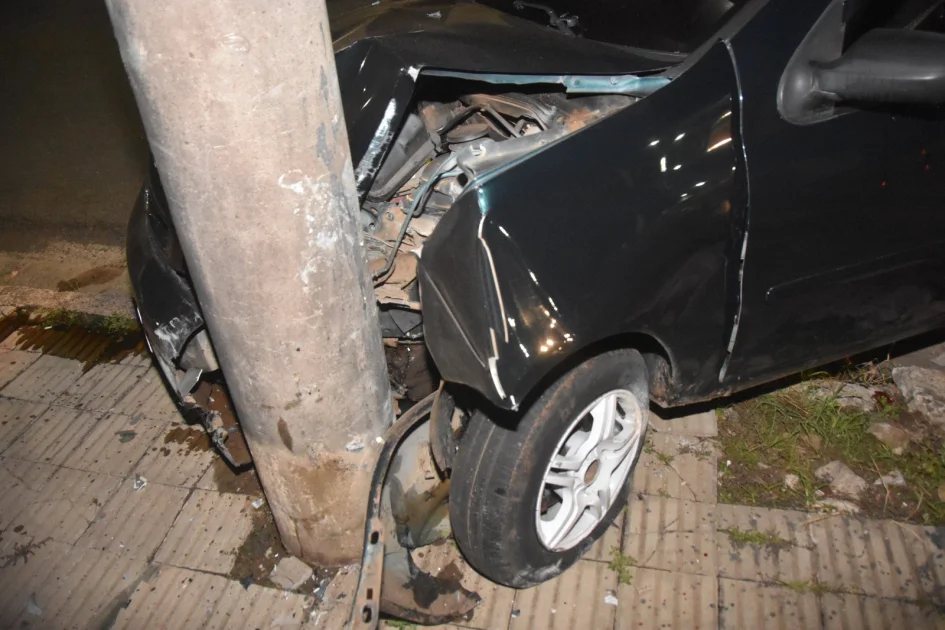Automóvil negro con severos daños frontales tras chocar contra una columna de hormigón